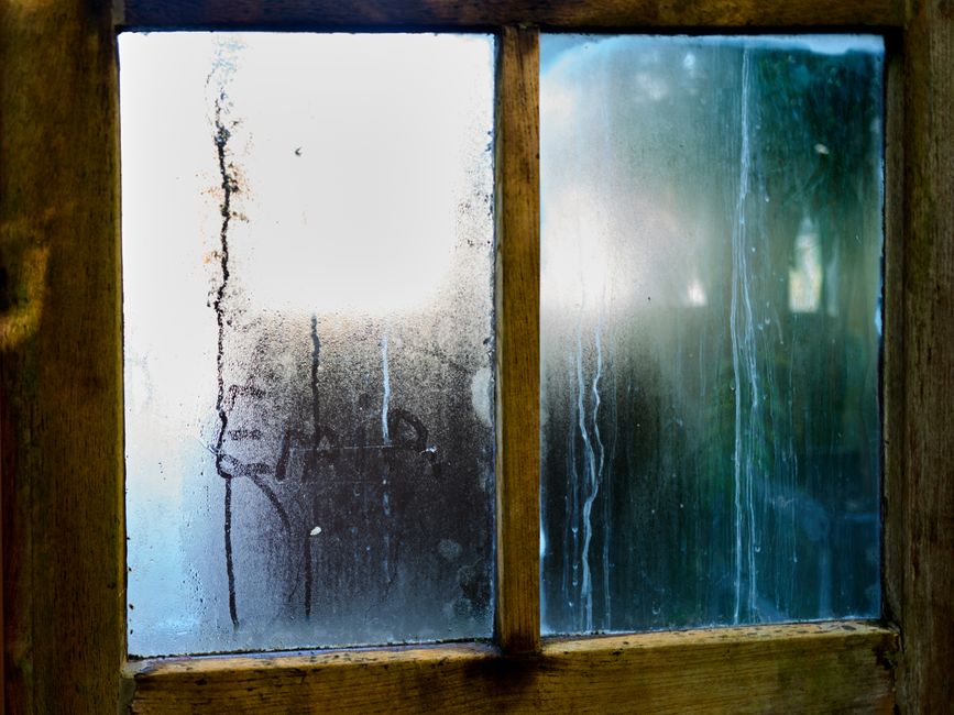 Close-up of a moist wooden window pane with condensation creating artistic streaks in Leiden, Netherlands.